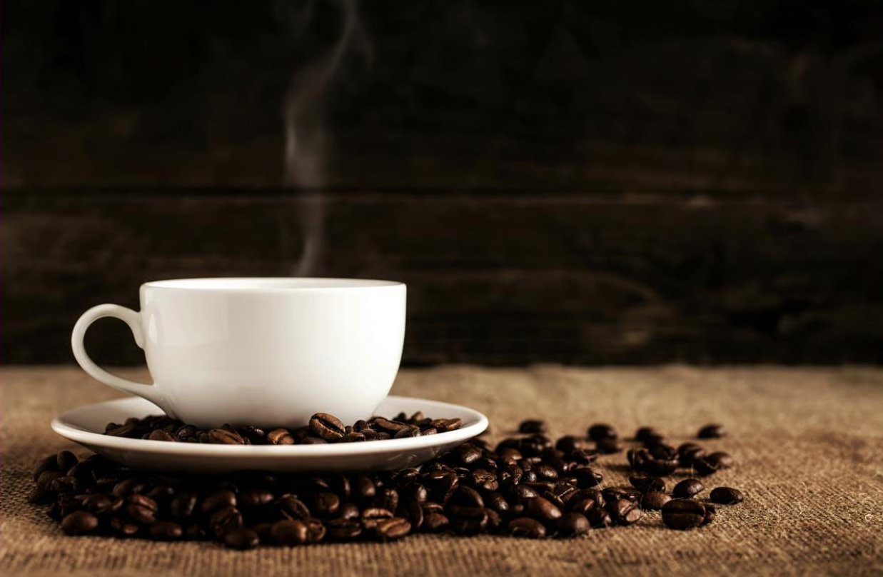 Dampfende Kaffeetasse auf gerösteten Bohnen