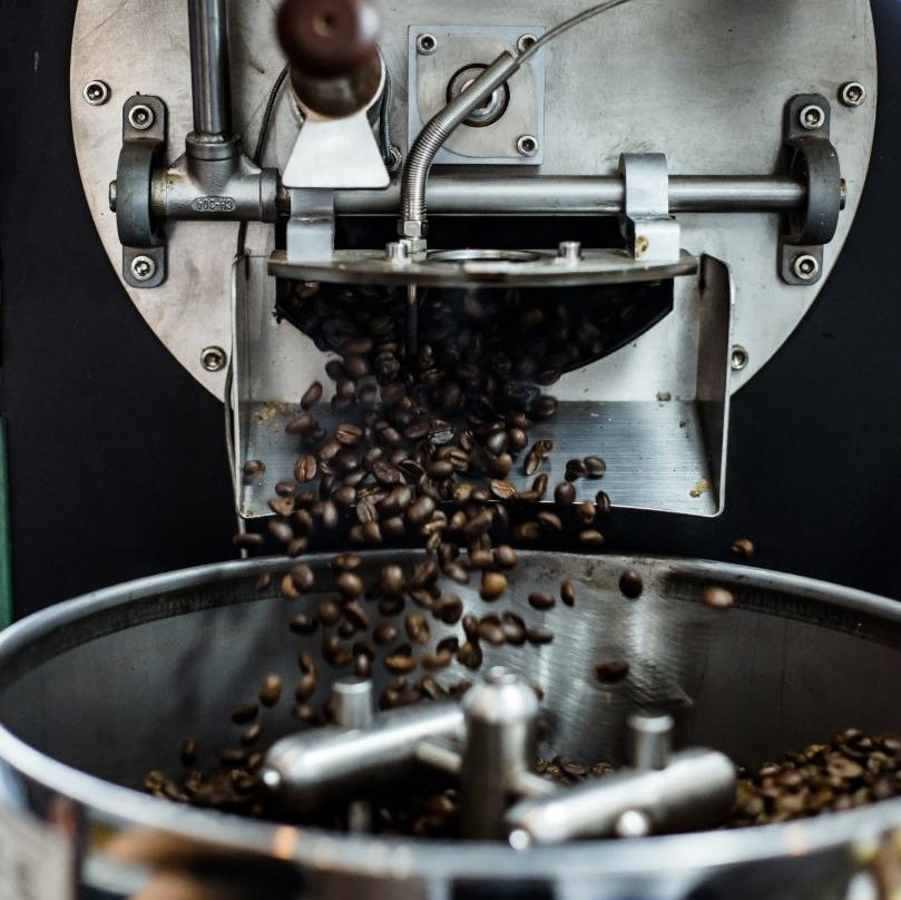 Kaffeebohnen fallen aus dem Röster ins Kühlsieb